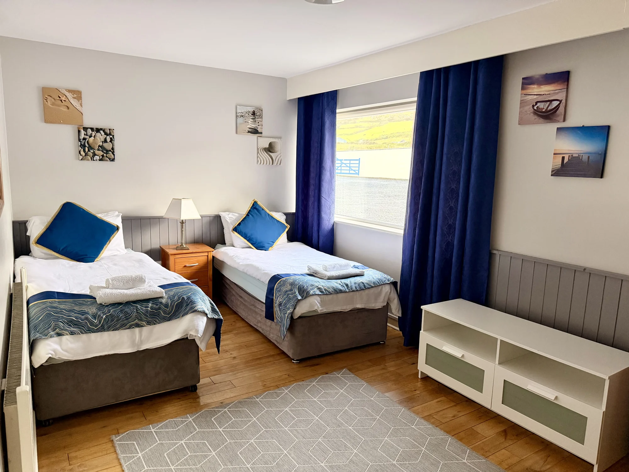Twin bedroom with blue curtains at Dolphin House