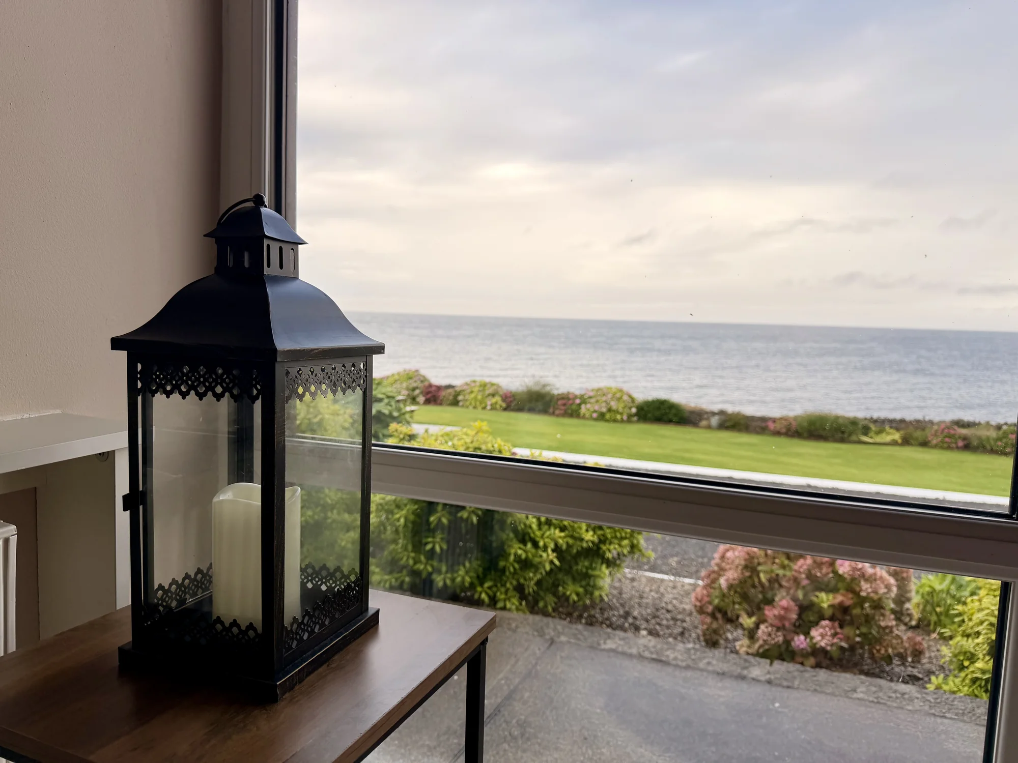 Lantern beside a window overlooking the garden and sea at Dolphin House