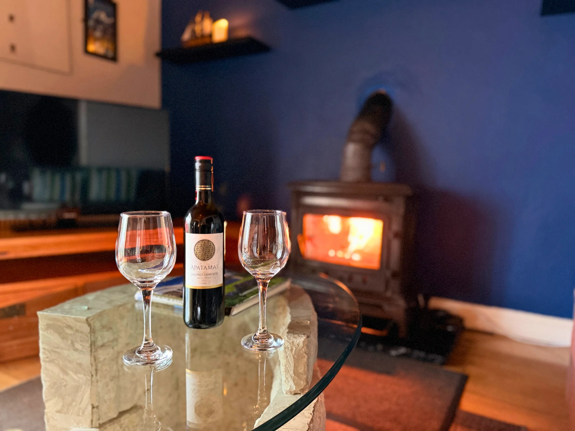 Wine glasses on a table beside the lit stove at Sailor’s Cabin