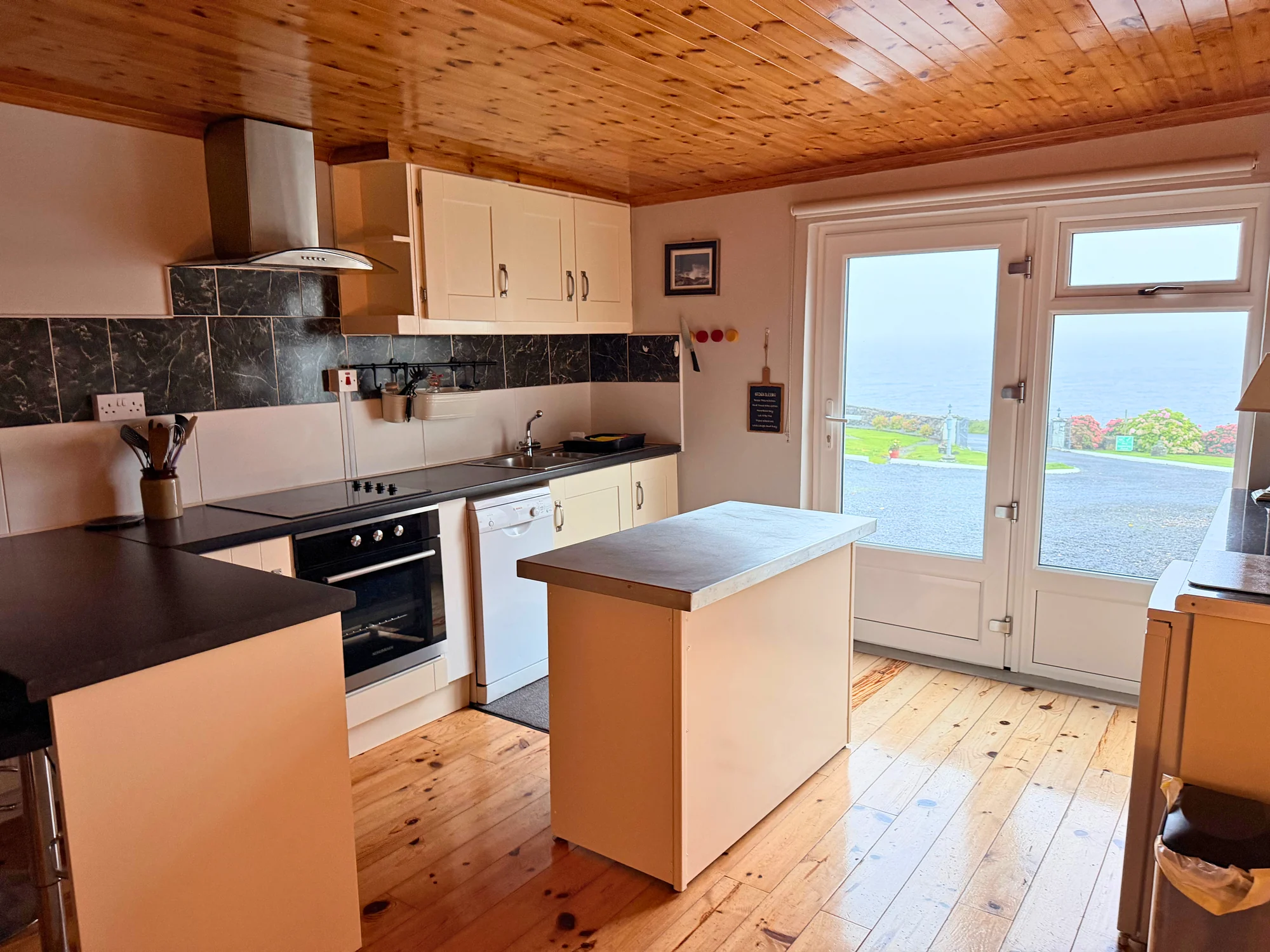 Kitchen and island beside doors overlooking the sea at Sailor’s Cabin